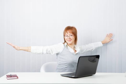 tired girl with a laptop stretches in the workplace