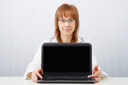 Attractive girl in glasses with a laptop in the office