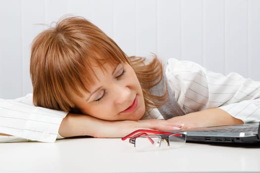 Tired girl lies on a table with a laptop