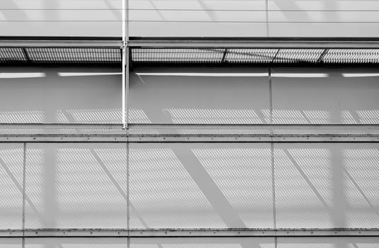 The close-up of a sheet metal façade with a scaffolding that casts shadows.