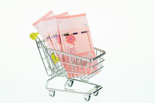 Malaysian ringgit in shopping cart over white background