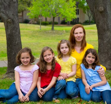 Mother teacher with daughter pupils in playground park group portrait on lawn