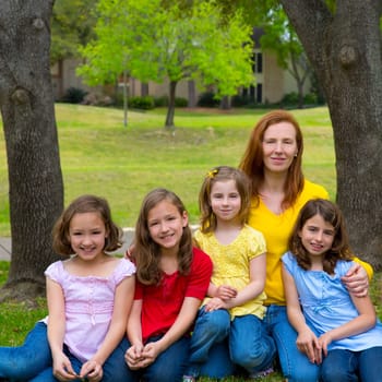 Mother teacher with daughter pupils in playground park group portrait on lawn