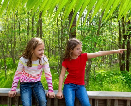 children sister friends playing relaxed pointing finger to jungle park forest outdoor