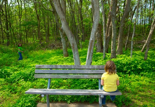 Lonely children sad looking the forest girl sitting at the park bench
