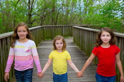 sister friends walking holding hands on lake wood smiling