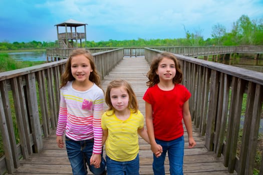 sister friends walking holding hands on lake wood smiling
