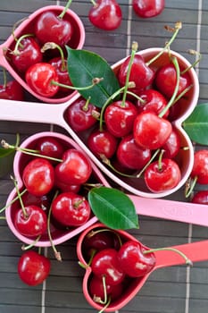 Fresh cherries in heart-shaped measuring cups