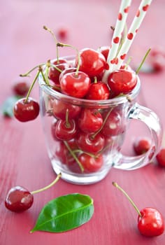 Fresh cherries in a glass cup with a straw