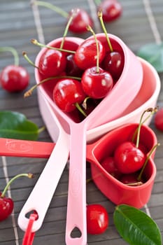 Fresh cherries in heart-shaped measuring cups