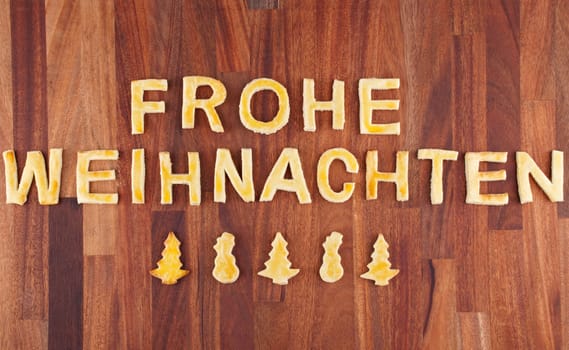 the german words Frohe Weihnachten, which means merry christmas with cookies