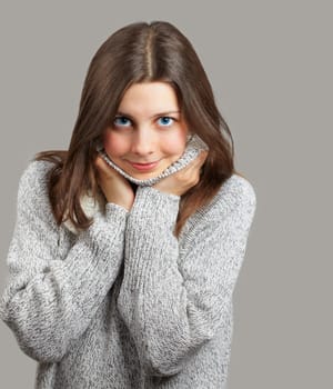Portrait of a beautiful young woman smiling over grey background.