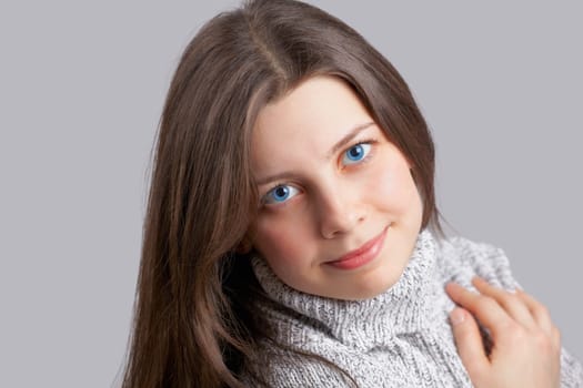 Portrait of a beautiful young woman smiling over grey background.