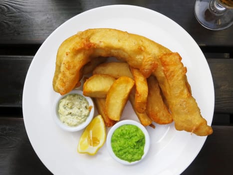 Fish and chips served with french fries, mushy peas and tartar sauce