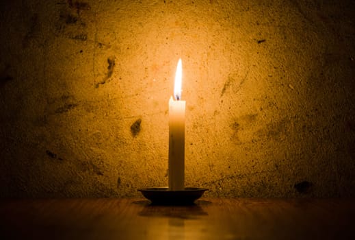 A candle burning, grungy wall background and vignette