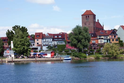 Waren,Mecklenburg Vorpommern/Germany – June 09,2013: People sit in a snack bar and walk along the promenade of Lake Mueritz on June 9th in Waren.