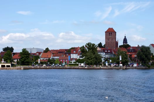Waren,Mecklenburg Vorpommern/Germany – June 09,2013: People sit in a snack bar and walk along the promenade of Lake Mueritz on June 9th in Waren.
