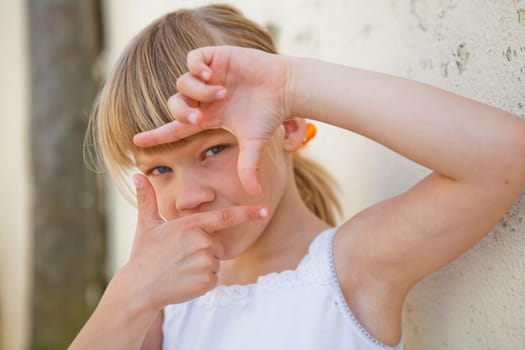 Closeup of cute young girl doing picture frame sign with fingers