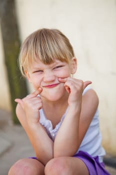 Portrait of cute smiling young girl making funny gesture with fingers on face
