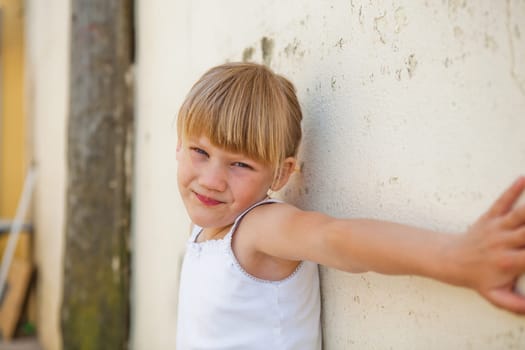 Portrait of cute young girl with arm stretched out against concrete wall