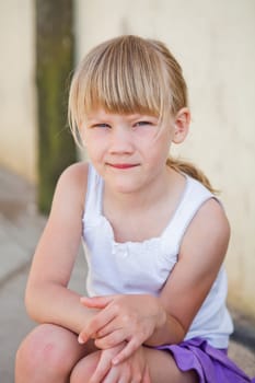 Portrait of cute young girl sitting in front of concrete wall outside