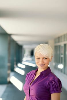 portrait of confident attractive business woman smiling and looking at camera out of office building. Copy space