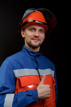 The worker in overalls and a helmet on a black background