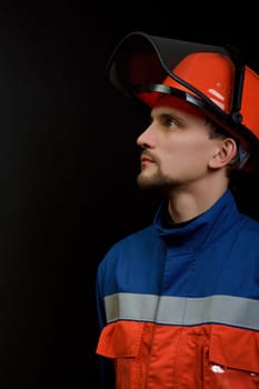 The worker in overalls and a helmet on a black background