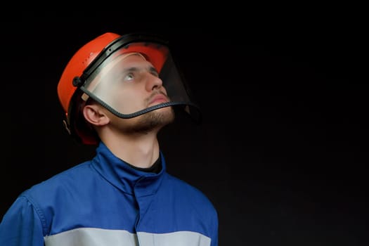 The worker in overalls and a helmet on a black background