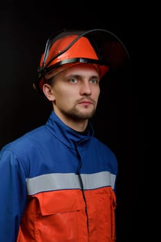 The worker in overalls and a helmet on a black background