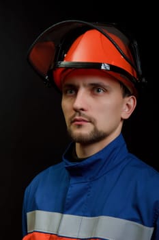 The worker in overalls and a helmet on a black background
