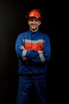 The worker in overalls and a helmet on a black background