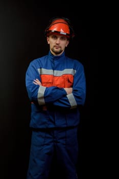 The worker in overalls and a helmet on a black background