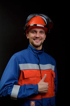 The worker in overalls and a helmet on a black background