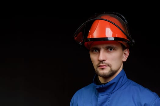 The worker in overalls and a helmet on a black background