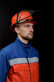 The worker in overalls and a helmet on a black background