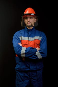 The worker in overalls and a helmet on a black background
