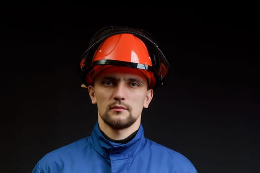 The worker in overalls and a helmet on a black background