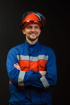 The worker in overalls and a helmet on a black background