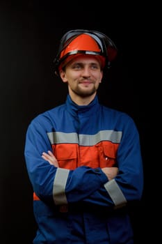 The worker in overalls and a helmet on a black background