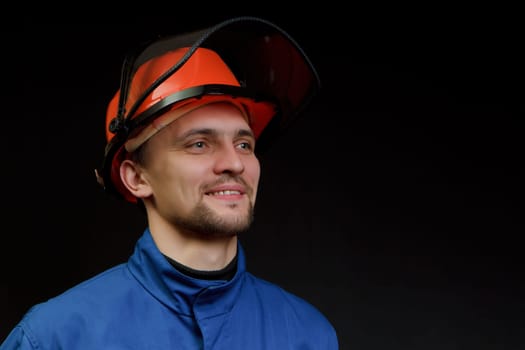 The worker in overalls and a helmet on a black background