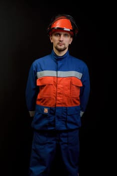 The worker in overalls and a helmet on a black background
