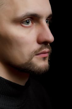 face of the young unshaven man in a black background