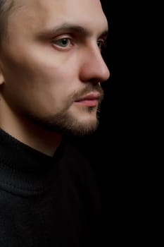 face of the young unshaven man in a black background