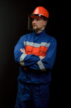 The worker in overalls and a helmet on a black background