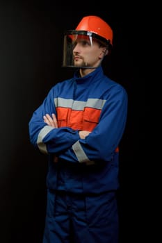 The worker in overalls and a helmet on a black background
