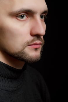 face of the young unshaven man in a black background