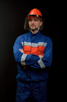 The worker in overalls and a helmet on a black background