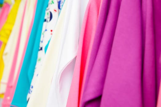 a lot of bright children's clothing on a hanger in the store