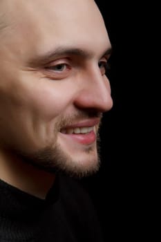 face of the young unshaven man in a black background
